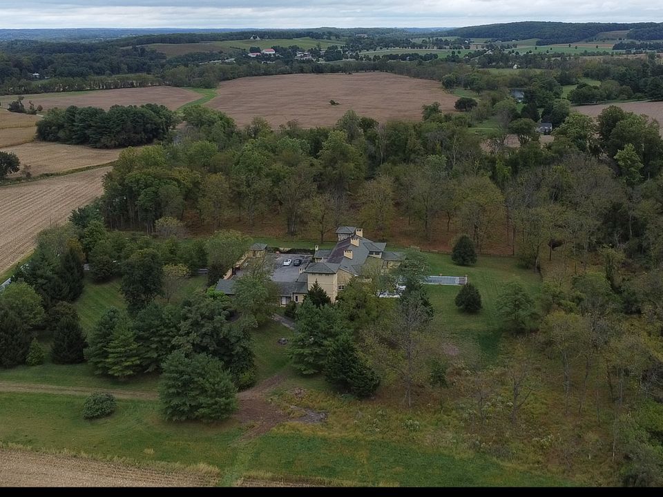 Drone photo of a country estate surrounded by woods, farm fields and rolling hills